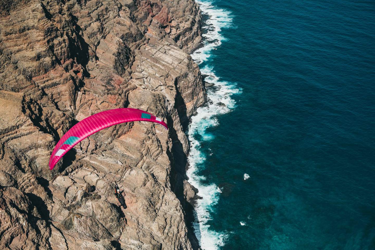 Pilote de hike & fly préparant son aile légère Niviuk étalée sur un décollage de montagne, prêt à transformer la descente en vol