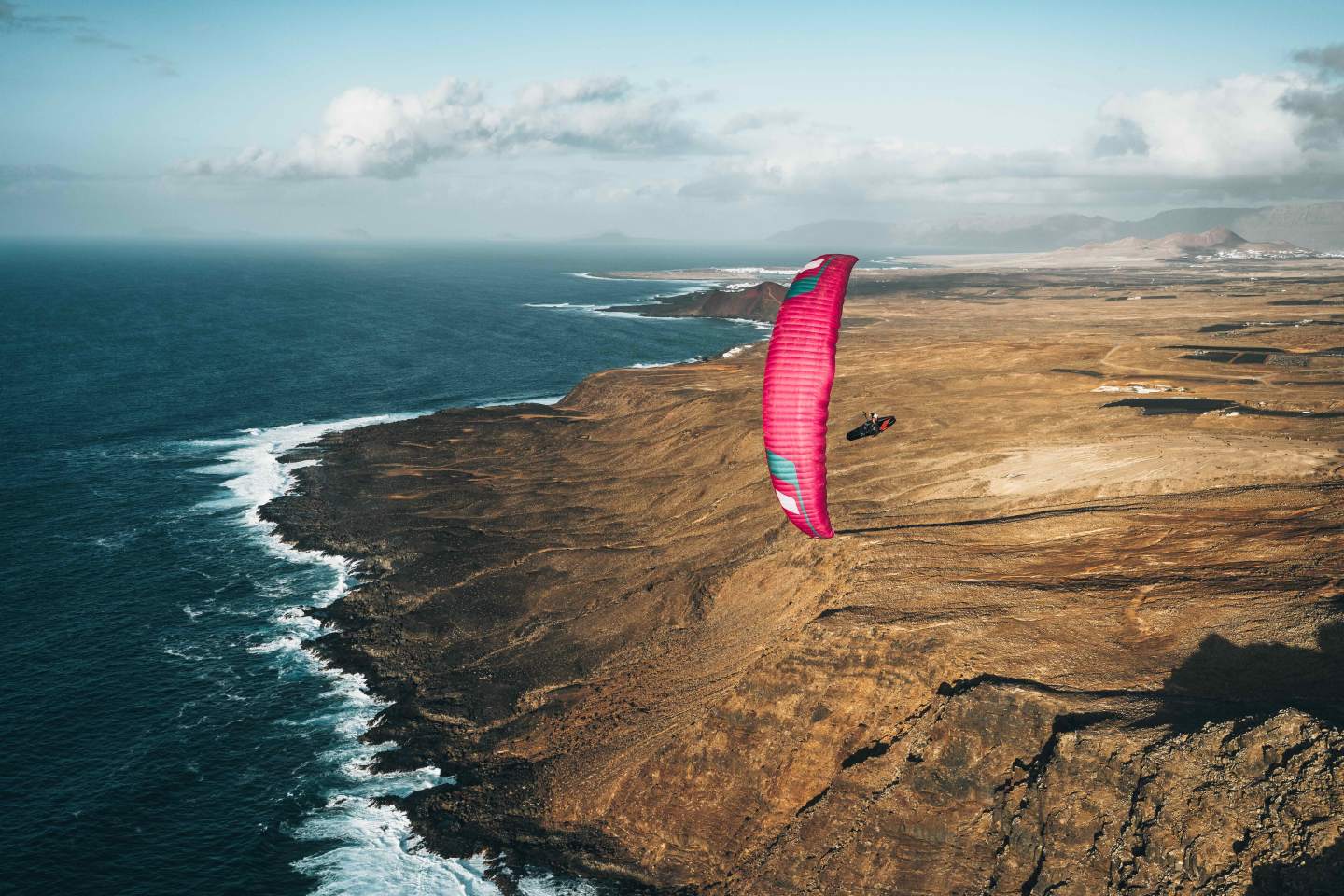 Aile de parapente légère en vol au-dessus de reliefs secs et ensoleillés, ambiance d’hiver doux typique d’un séjour hike & fly en Espagne