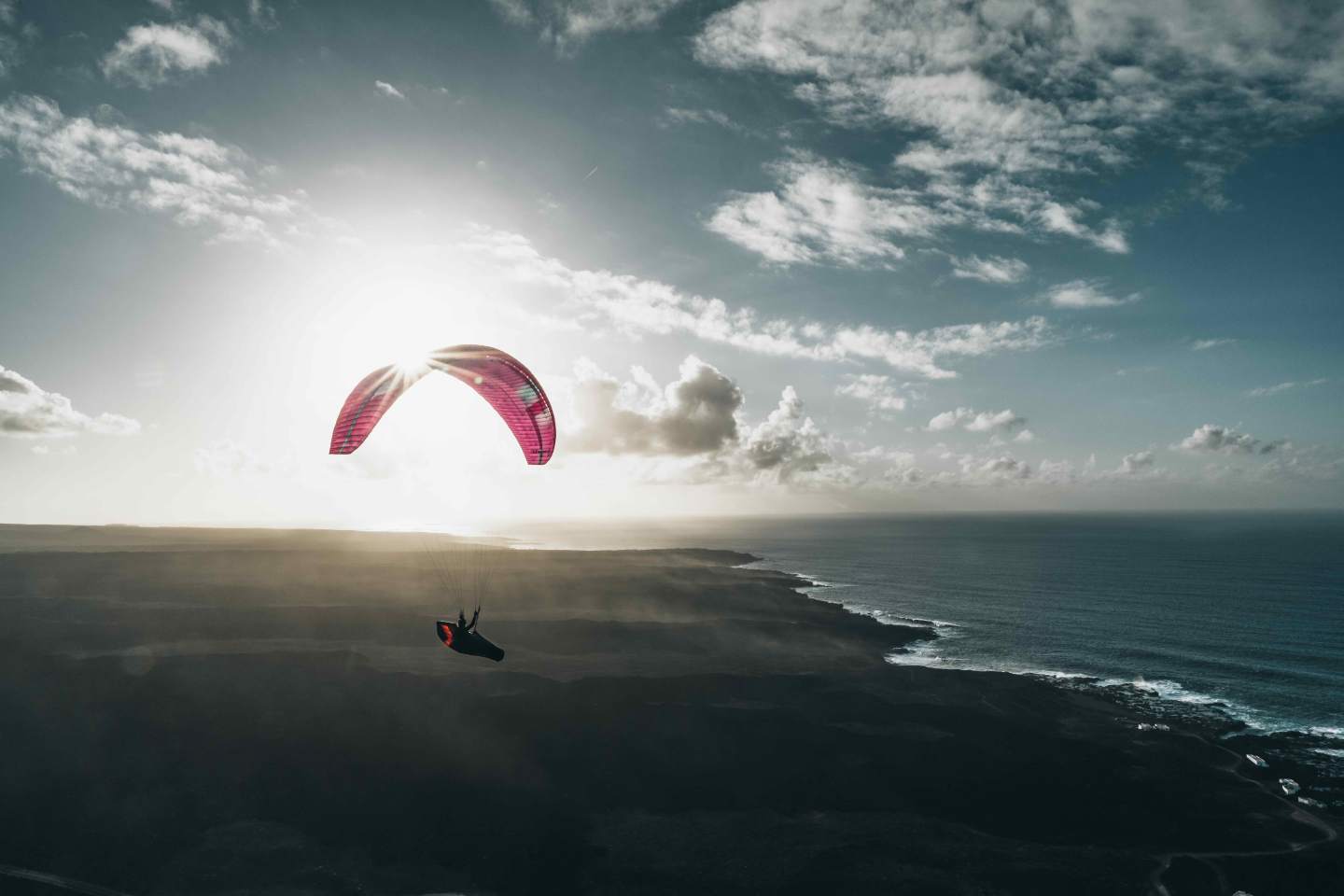 Voile de parapente légère en vol au ras d’une pente alpine, ambiance de crêtes et de vallées typique des Alpes de l’Est.