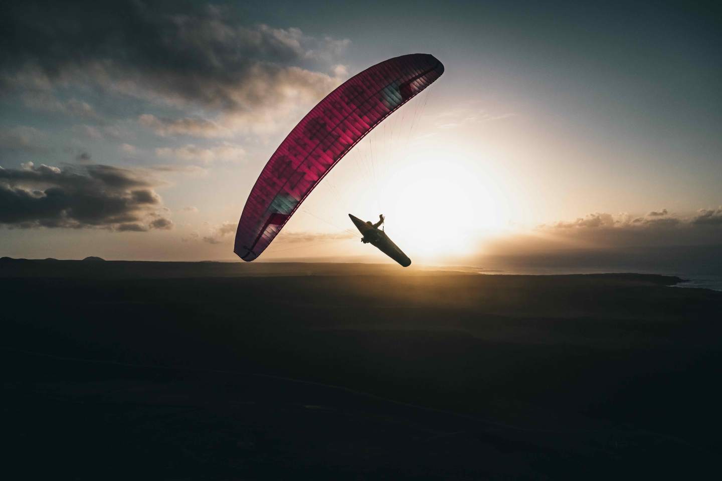 Parapente en contre-jour au coucher du soleil sur une crête