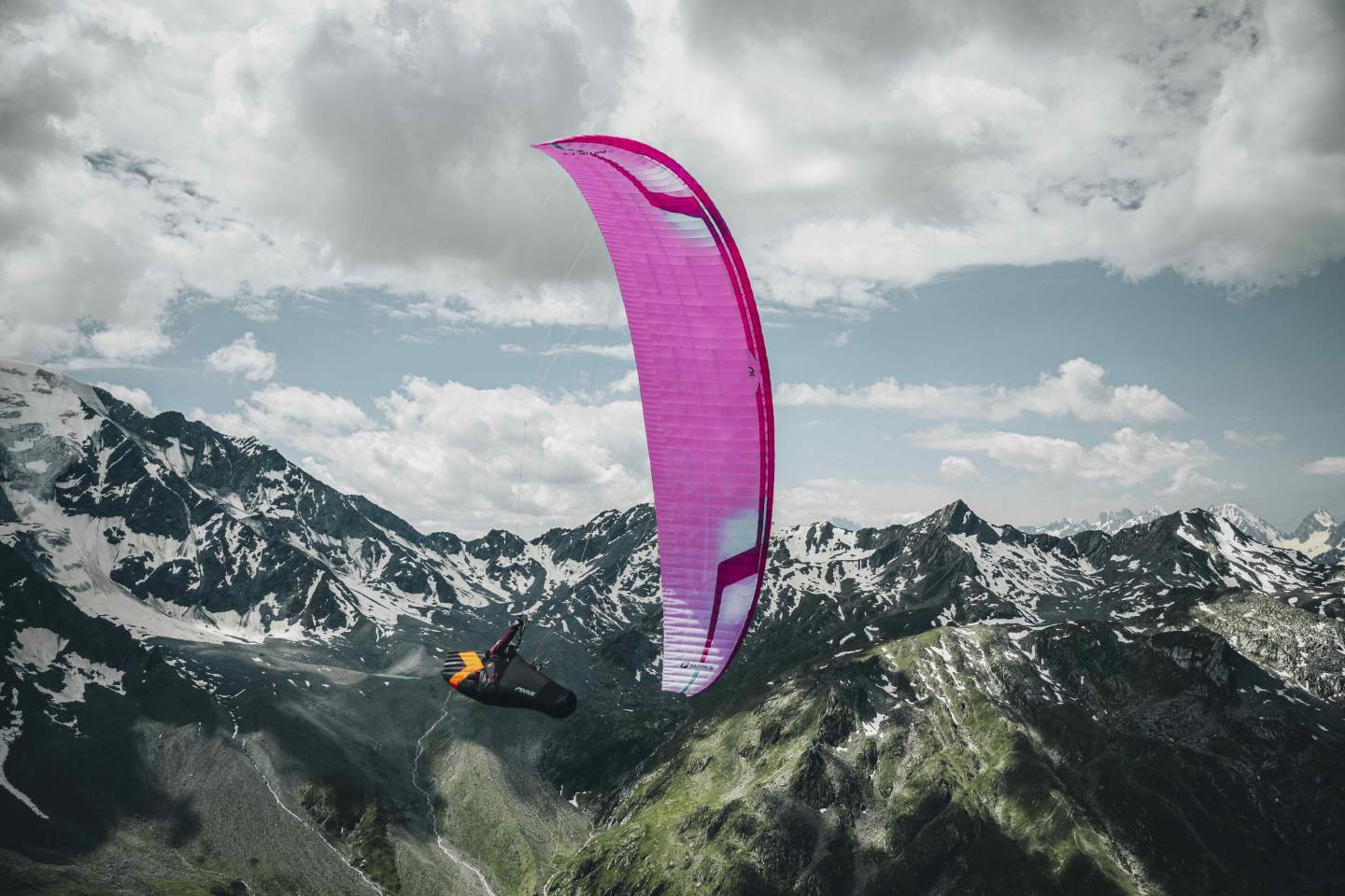 Parapente léger enroulant un thermique au-dessus d’un relief de montagne en fin de matinée, pilote seul en air actif.
