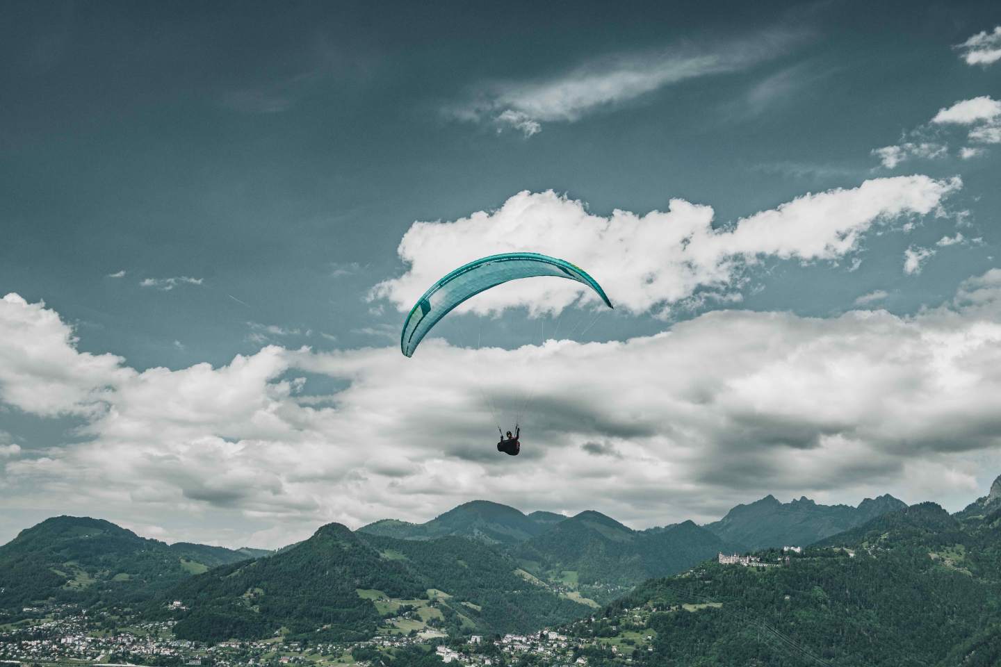 Parapentiste hike & fly redescendant à pied par un sentier de crête, voile pliée et sanglée sur le sac à dos, sous un ciel de fin de journée en montagne.