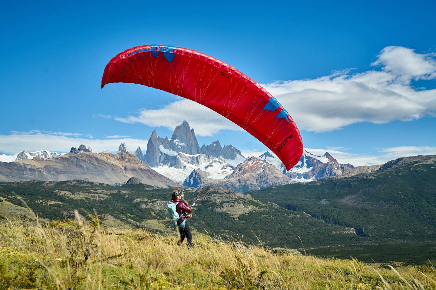 Pilote lançant une voile légère de hike & fly, matériel sur le dos