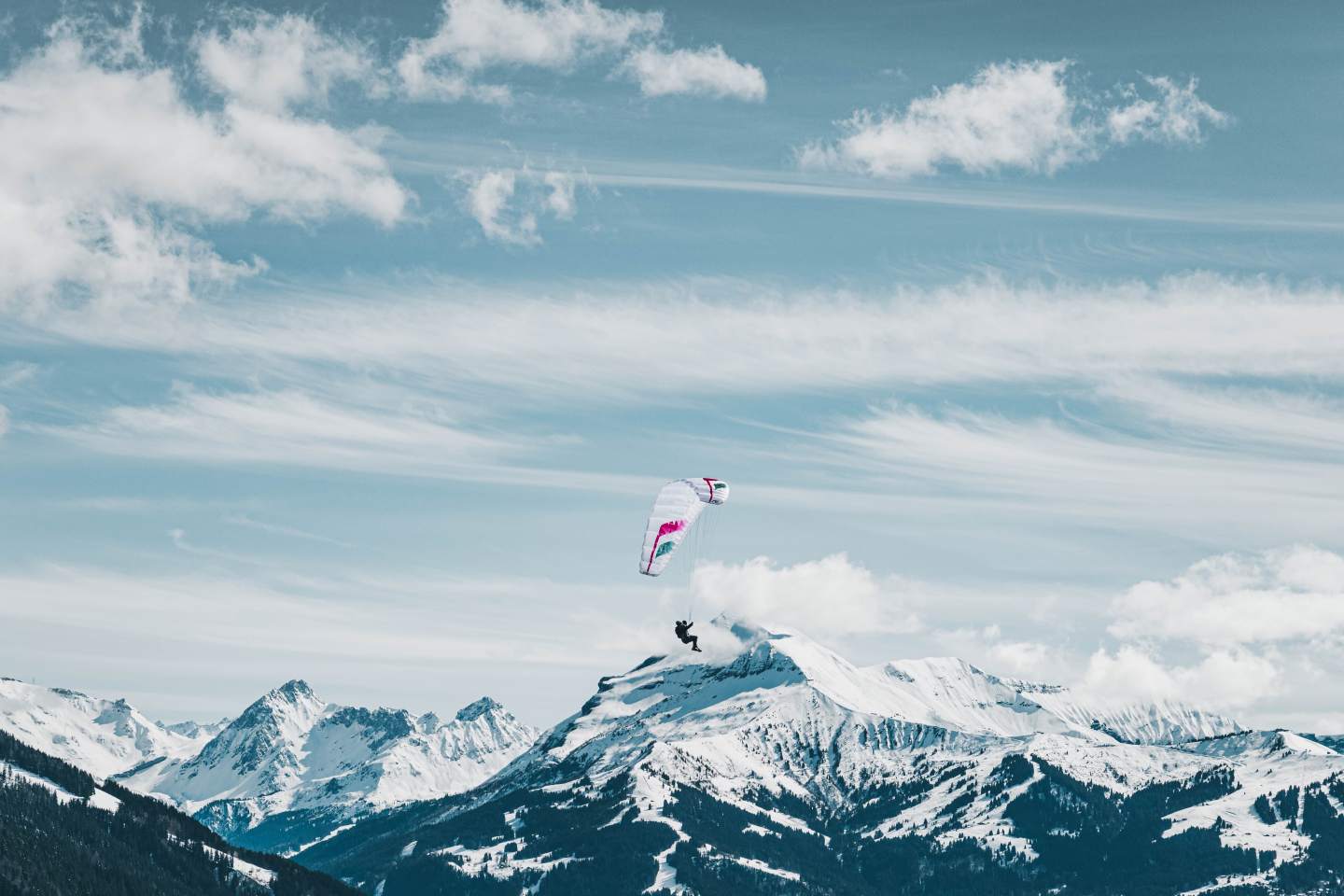 Pilote en approche d’un décollage de montagne, voile Niviuk pliée sur le sac, chaussures posées sur une pente herbeuse raide typique d’un déco hike & fly.